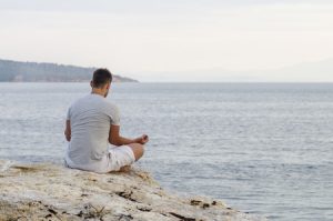 Mann meditiert am Strand