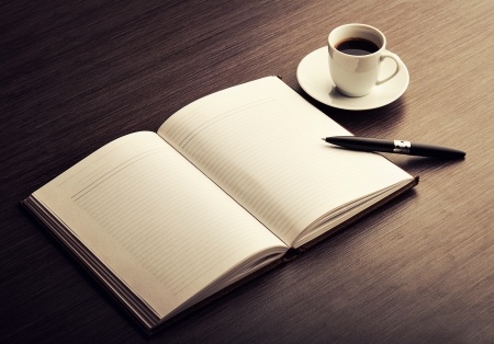 Offenes Buch mit Tasse Kaffee und Stift